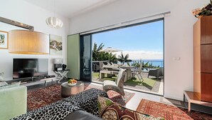 A modern living room with a large TV, comfortable seating, and a view of the outdoors.
