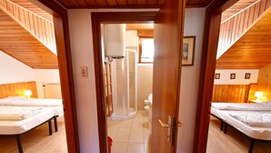 Een kamer met twee bedden, een douche en een houten plafond.