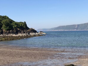 A coastal beach with rocky terrain and clear blue water.