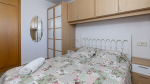 Ein Schlafzimmer mit Bett, Holzschrank und Spiegel.