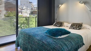 A bedroom with a large bed, two bedside lamps, and a view of buildings through a window with blinds. - My Space Barcelona 9 Apart has 54 people with optional parking in the center (Barcelona)