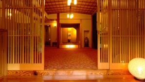 Un interior tradicional amb portes corredisses de fusta, una recepció central i un sòl de fusta polida.
