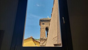 Une vue par la fenêtre sur un bâtiment doté d’une tour et d’un cadre de porte.
