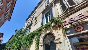 Un bâtiment avec une porte verte, une enseigne sur laquelle on peut lire « TRAE » et « TRASTEVERE CALCIO », et une fenêtre ornée d’une grille décorative.