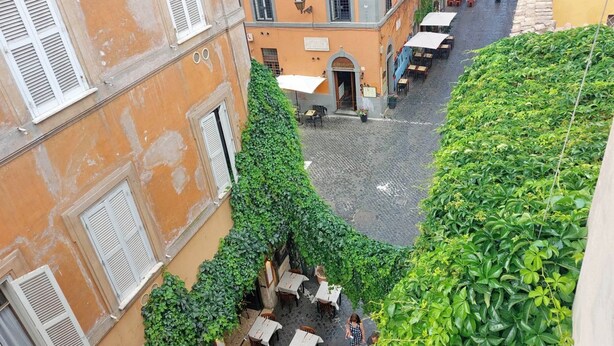 Une rue étroite avec des tables en terrasse, un immeuble avec une porte et un escalier.
