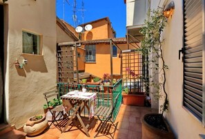 A small patio with a table and chairs, potted plants, and a green metal fence. - Rome, Trastevere, comfortable apartment for 6 (Roma)