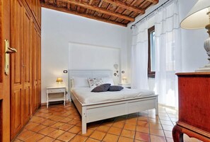 A bedroom with a white bed, wooden wardrobe, tiled floor, and a wooden ceiling. - Rome, Trastevere, comfortable apartment for 6 (Roma)