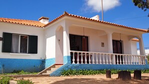 A two-story house with a balcony, a tiled roof, and a small porch area.
