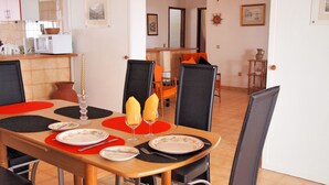 A dining area with a wooden table set for two, black and red placemats, and a candle centerpiece.