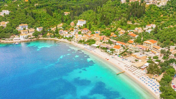 Vue aérienne d’une ville côtière avec une plage, des maisons et une mer bleue et limpide.