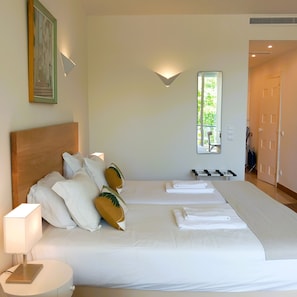 Habitación de hotel con una cama grande, una mesita de noche con lámpara, un espejo y vistas al exterior.
