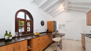 Eine Küche mit Holdekor-Schränken, einer Marmorarbeitsplatte, einem großen Fenster und einem Barhocker.
