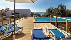 A wooden deck with lounge chairs and a pool, overlooking a coastal area. - Villa Diane, Luxury Cottage, Ocean views, pool (Benagil)