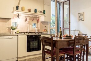 A kitchen with a dishwasher, oven, and a dining table with chairs.
