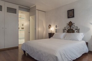 Una camera da letto con un letto grande, un armadio, un comodino con una lampada e un quadro appeso al muro.