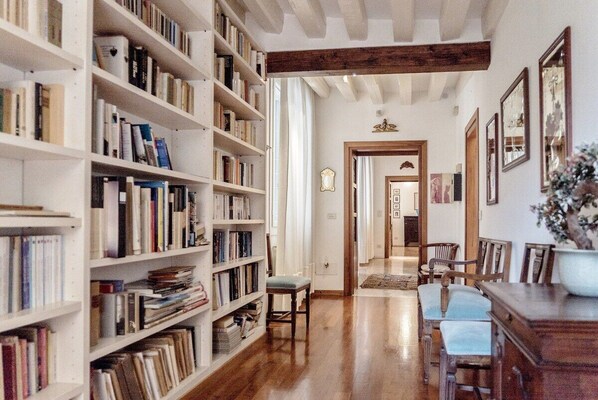 A library with bookshelves, a wooden floor, and a dining area with chairs and a table.