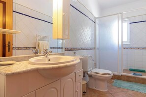 A bathroom with a sink, toilet, and shower area.