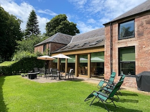A brick house with a patio area featuring outdoor furniture and umbrellas. - Fabulous open plan house in country estate - 4 bedrooms, each with its own bathroom (By Arbroath)