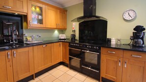 A kitchen with wooden cabinets, a black stove, and a wall clock.
