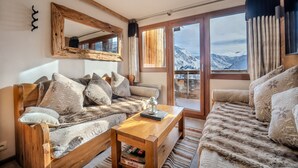 Un salon chaleureux avec un canapé en bois, une table basse et une grande fenêtre donnant sur une vue imprenable sur les montagnes.
