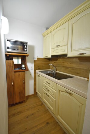 Une cuisine compacte avec des meubles en bois, un four à micro-ondes encastré et un évier.