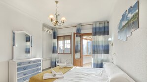 A bedroom with a bed, a dresser, a mirror, and a window with curtains. - Villa Garrofer- PlusHolidays (Calpe)