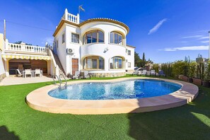 Una casa de dos pisos con piscina, un patio cubierto y una escalera que lleva al piso superior.