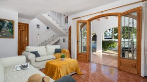 A spacious living area with a staircase, a sofa, a coffee table, and a view of the outside. - Villa Padilla - PlusHolidays (Benissa)