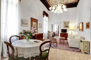 A room with a dining table, chairs, a sofa, a television, and framed pictures on the walls.