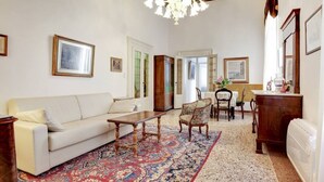Ein Wohnzimmer mit einer Couch, einem Couchtisch, einem gemusterten Teppich, einer Pendelleuchte und gerahmten Bildern an den Wänden.