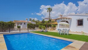 Une piscine avec une terrasse carrelée, un patio couvert et une vue sur les maisons environnantes.