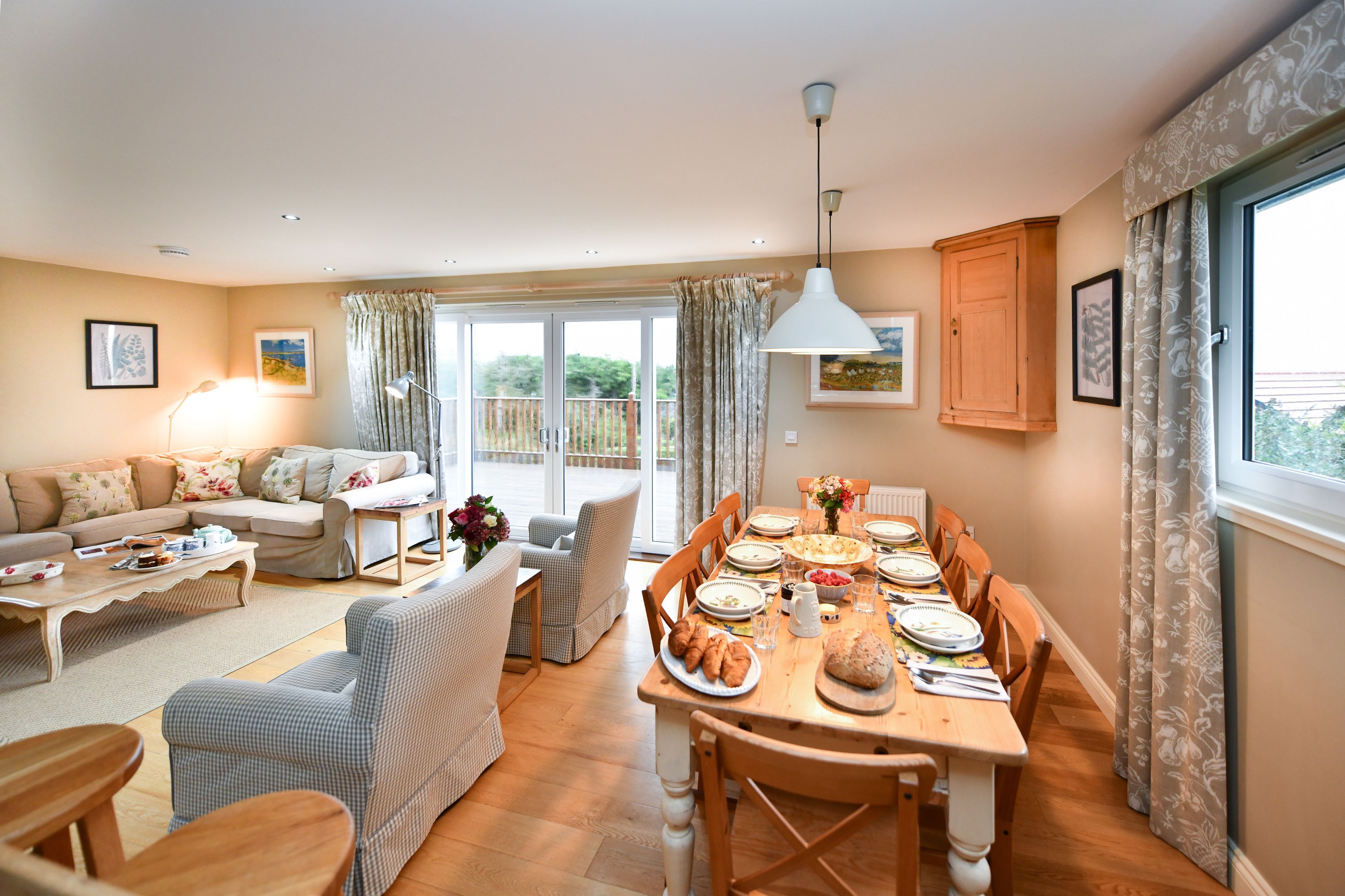 A spacious living room with a dining area, large windows, and a balcony.