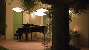 A grand piano in a well-lit room with a green door and a small table with a candle. - YOUR HOME AWAY FROM HOME (Treviso)
