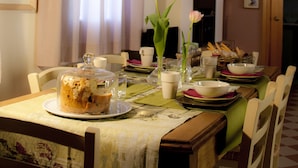 A dining table set with plates, bowls, and a cake in a room with chairs and a fireplace. - YOUR HOME AWAY FROM HOME (Treviso)
