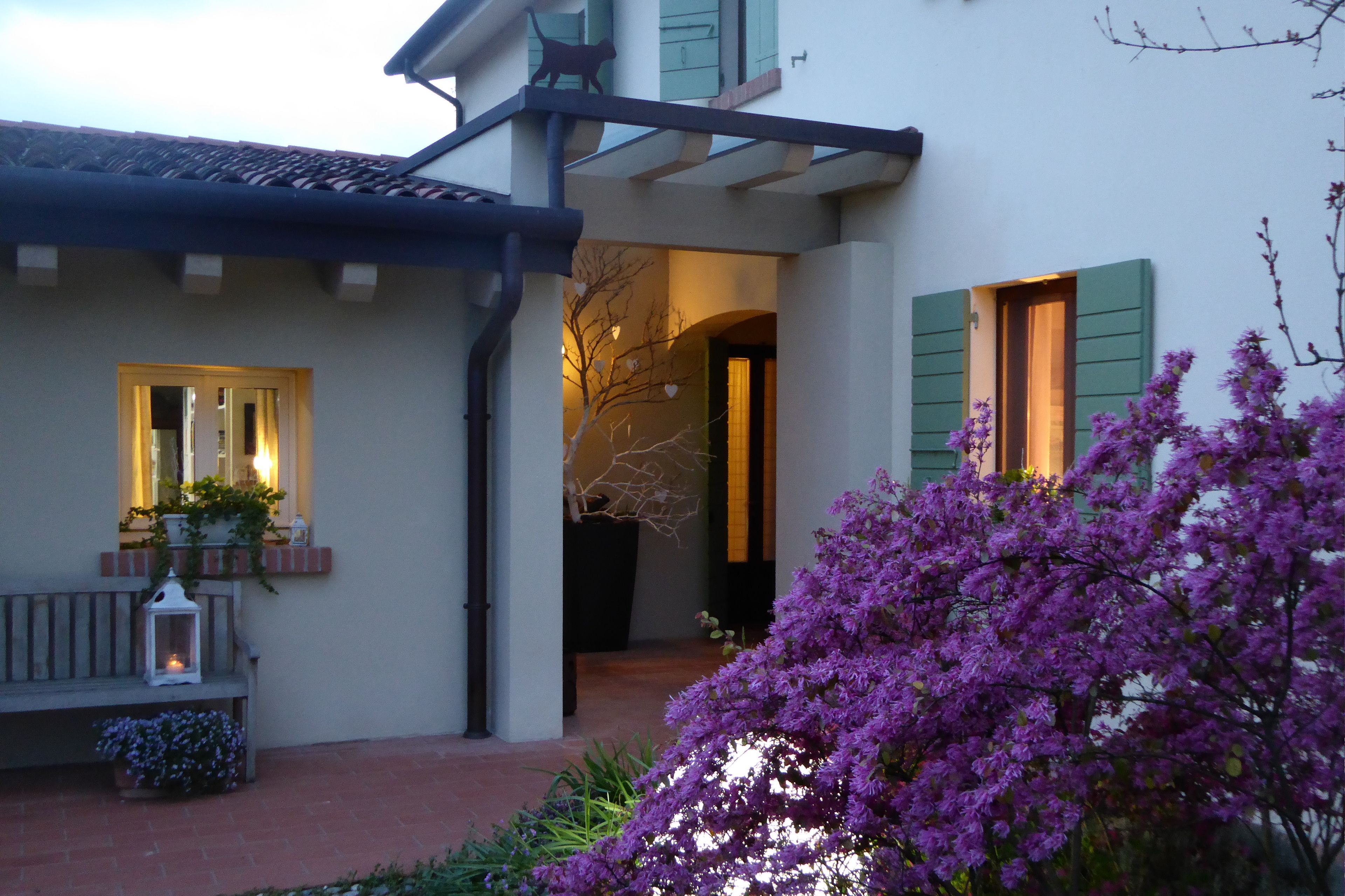 Una casa con porche cubierto, un banco y una planta en maceta.