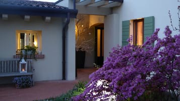 Una casa con porche cubierto, un banco y una planta en maceta.