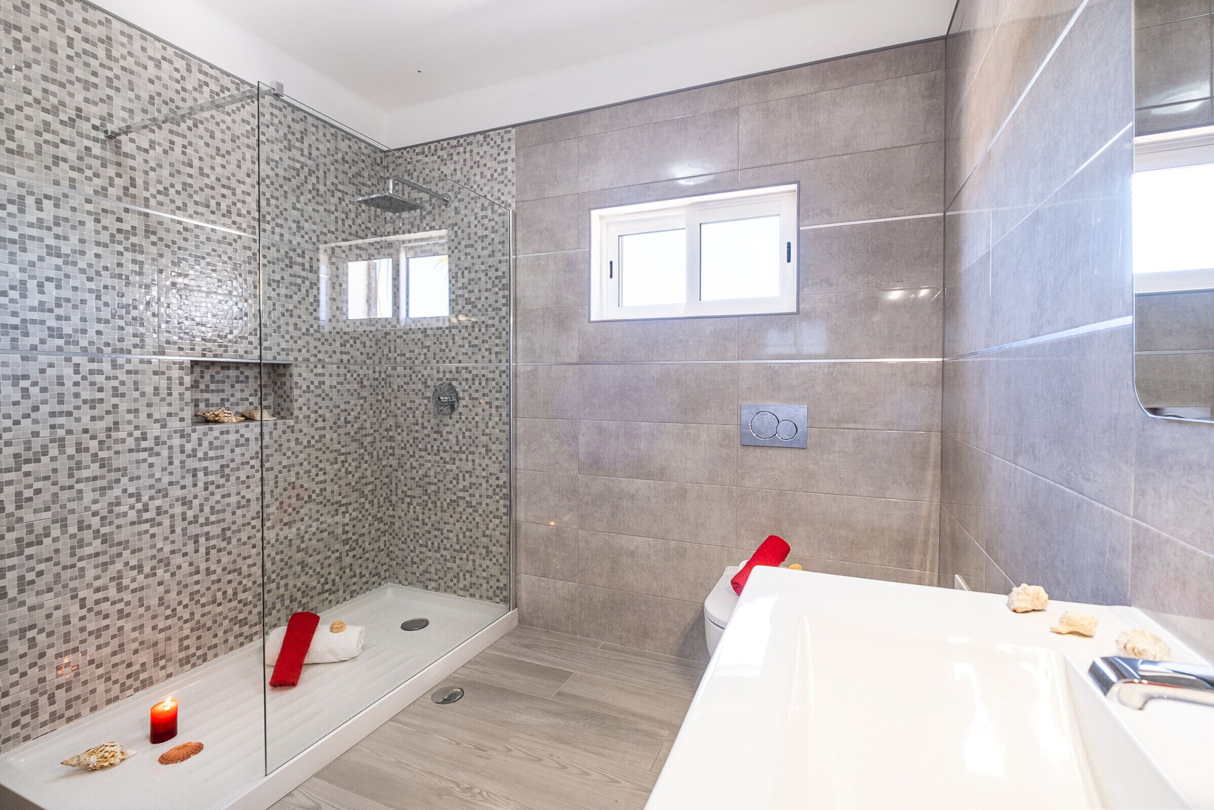 A modern bathroom with a glass shower enclosure, a white bathtub, and a large mirror.