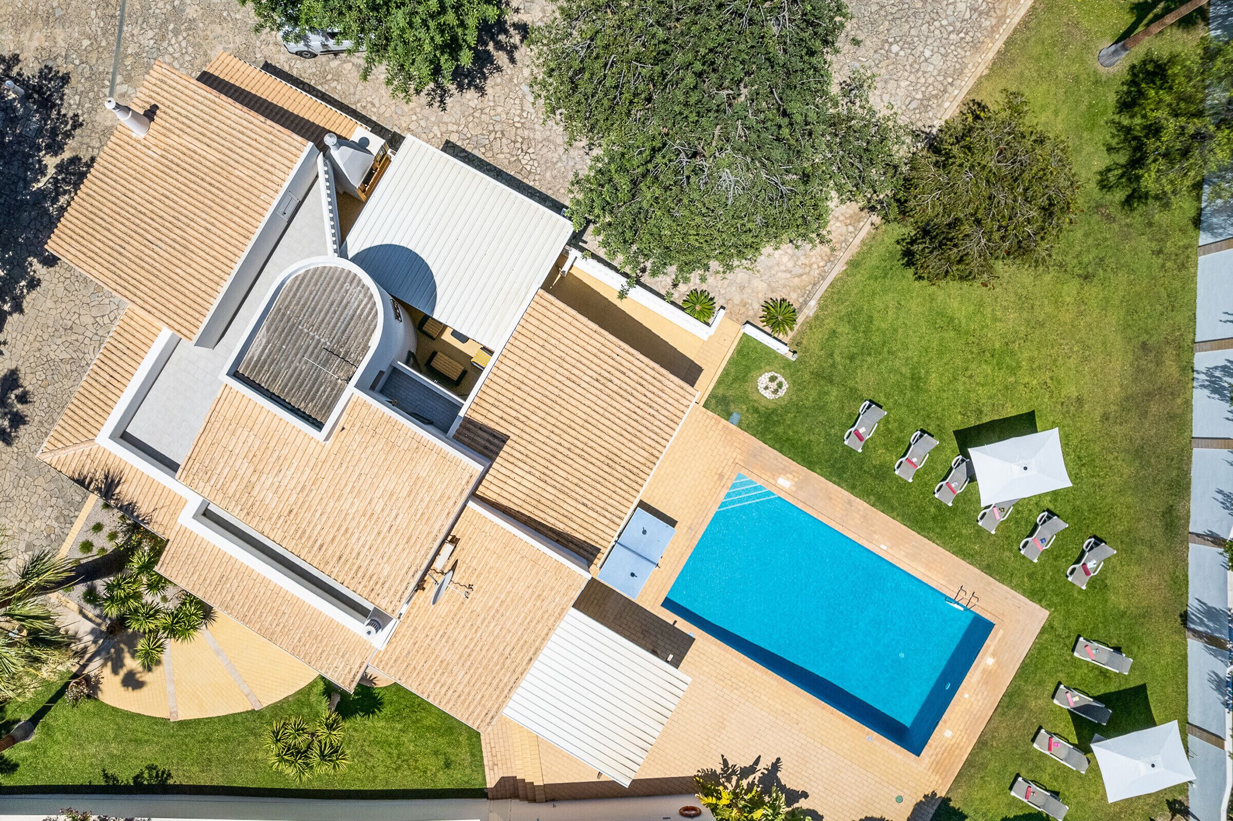 An aerial view of a modern house with a swimming pool, a covered patio, and a well-maintained lawn.