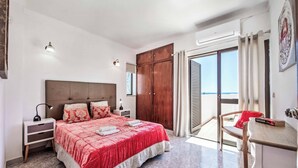 Ein Schlafzimmer mit einem Bett, Nachttischen, einem Holzschrank, einem Schreibtisch und einem Stuhl.