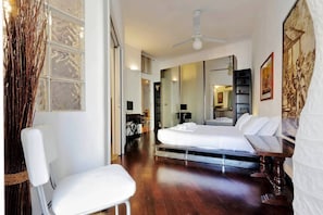 Une chambre d’hôtel moderne équipée d’un lit, d’une chaise, d’un bureau et d’un grand miroir.