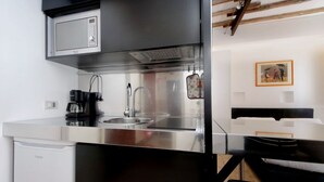 Cocina compacta con microondas, cafetera y lavabo.