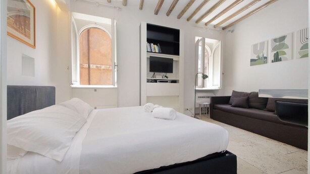 Un dormitorio moderno con cama, escritorio, sofá y televisor.