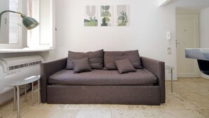 Una sala moderna con un sofá gris, una lámpara de pie y arte abstracto en la pared.