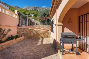 Un patio con suelo de piedra, una parrilla y vistas a un paisaje montañoso.