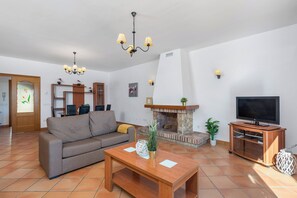 A living room with a sofa, a TV, a fireplace, and a chandelier. - Villa Amanda - Plusholidays (Calpe)