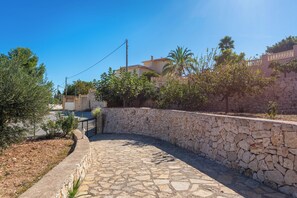 A stone pathway leading to a building with a stone wall and vegetation. - Villa Amanda - Plusholidays (Calpe)