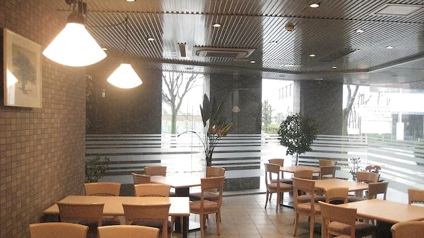 Ein Restaurant mit Holztischen und -stühlen, einer Ziegelwand und großen Fenstern.