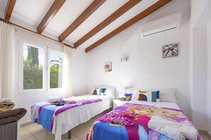 A room with two beds, a window, and an air conditioning unit.