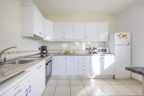 A kitchen with white cabinets, a microwave, and a refrigerator with a world map.