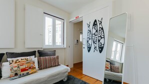 Ein kompakter Raum mit einem Bett, einer kleinen Couch, einem Spiegel und einer Wand mit Fischmotiven.
